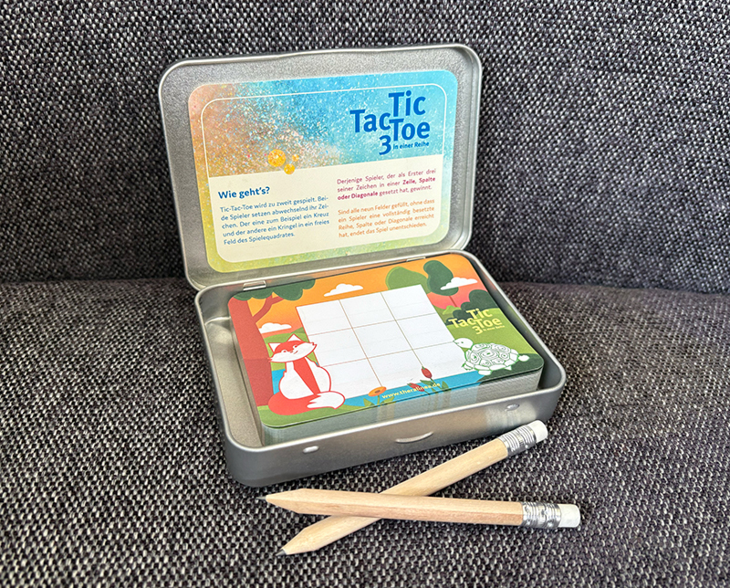 Ein Block und zwei Bleistifte in einer Metallbox zum Spielen von TicTacToe